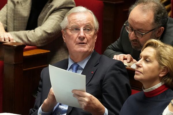 French Prime Minister Michel Barnier holds a document during speeches at the National Assembly prior to a no-confidence vote that could bring down the Prime Minister and the government for the first time since 1962, Wednesday, Dec. 4, 2024 in Paris. (AP Photo/Michel Euler)