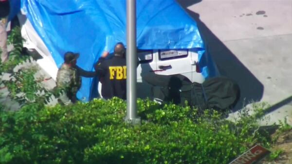 In this frame grab from video provided by WPLG-TV, FBI agents cover a van parked in Plantation, Fla., on Friday, Oct. 26, 2018, that federal agents and police officers have been examining in connection with package bombs that were sent to high-profile critics of President Donald Trump. The van has several stickers on the windows, including American flags, decals with logos and text. (WPLG-TV via AP)