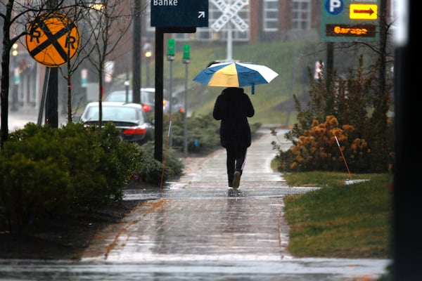 A person walks through the rain as a storm system and possible "bomb cyclone" hit the U.S. East Coast, Wednesday, Dec. 11, 2024 in Portsmouth, N.H. (AP Photo/Caleb Jones)