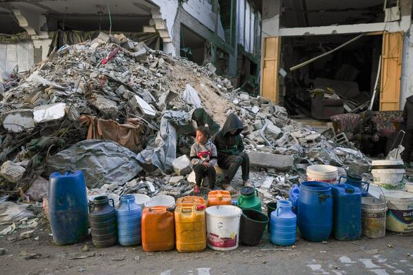 Two children wait to get water next to a line of empty jerrycans in an area largely destroyed by the Israeli army's air and ground offensive in Gaza City, Gaza Strip, Wednesday, Feb. 5, 2025. (AP Photo/Abdel Kareem Hana)