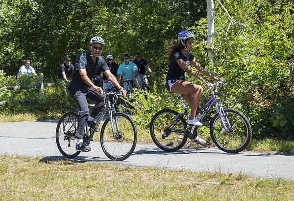 U.S. President Barack Obama and daughter Malia Obama ride bikes along the Correllus State Bike Path on August 15,  2014 outside of West Tisbury, Martha's Vineyard, Massachusetts.   (Photo by Rick Friedman-Pool/Getty Images)