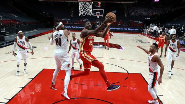 Hawks center Clint Capela shoots between Trail Blazers forward Carmelo Anthony (left) and guard CJ McCollum (right) during the first half Saturday, Jan. 16, 2021, in Portland, Ore. (Craig Mitchelldyer/AP)