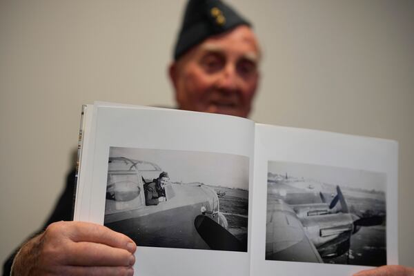 Michael Woods, 100-year-old World War II veteran, shows a photo of himself during an interview in Dunstable, Bedfordshire, England, Tuesday, Nov. 5, 2024. (AP Photo/Kin Cheung)