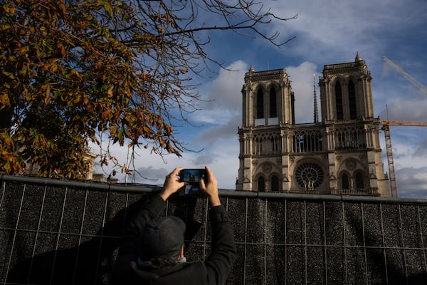 A visitor takes photographs of Notre-Dame cathedral in Paris, Wednesday, Nov. 20, 2024. (AP Photo/Louise Delmotte)