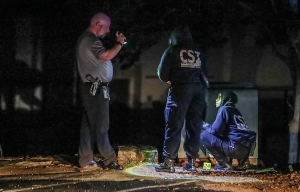 DeKalb County police examine evidence from the scene of a shooting at an apartment complex on Maypop Lane.