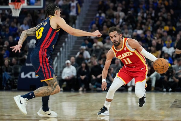 Atlanta Hawks guard Trae Young, right, moves the ball while defended by Golden State Warriors forward Lindy Waters III during the first half of an NBA basketball game Wednesday, Nov. 20, 2024, in San Francisco. (AP Photo/Godofredo A. Vásquez)