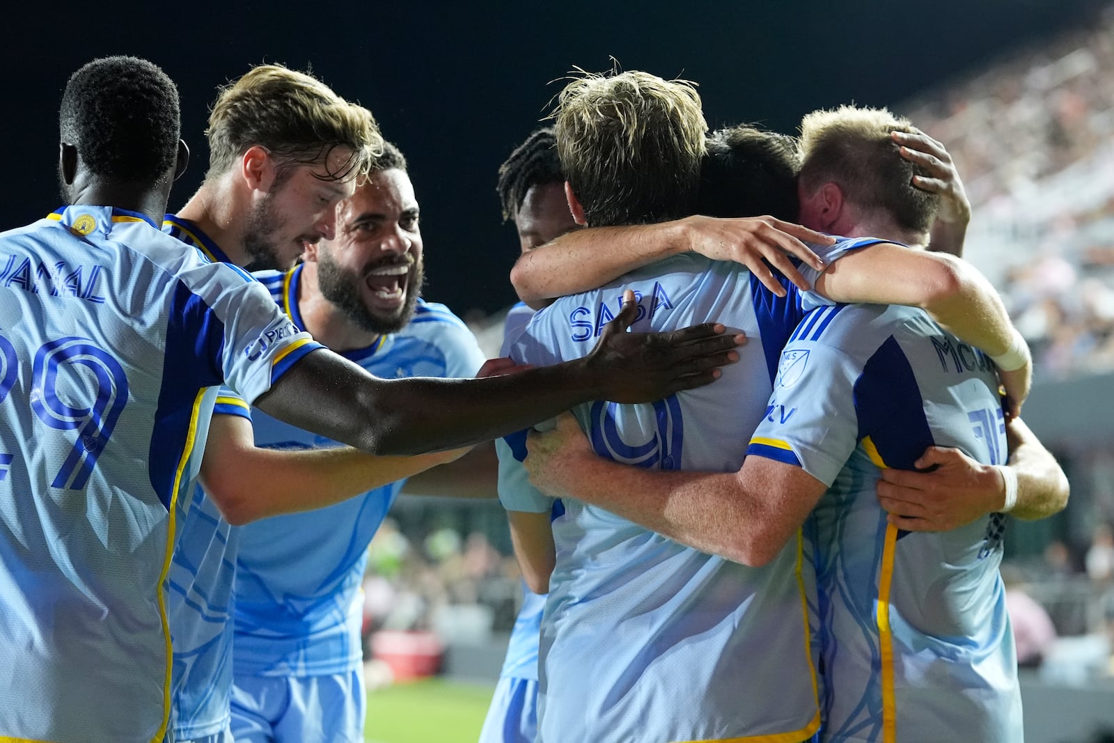 Atlanta United midfielder Saba Lobzhanidze (9) is congratulated by his teammates after scoring a goal during the first half of match one of their MLS playoff opening round soccer match against Inter Miami, Friday, Oct. 25, 2024, in Fort Lauderdale, Fla. (AP Photo/Rebecca Blackwell)