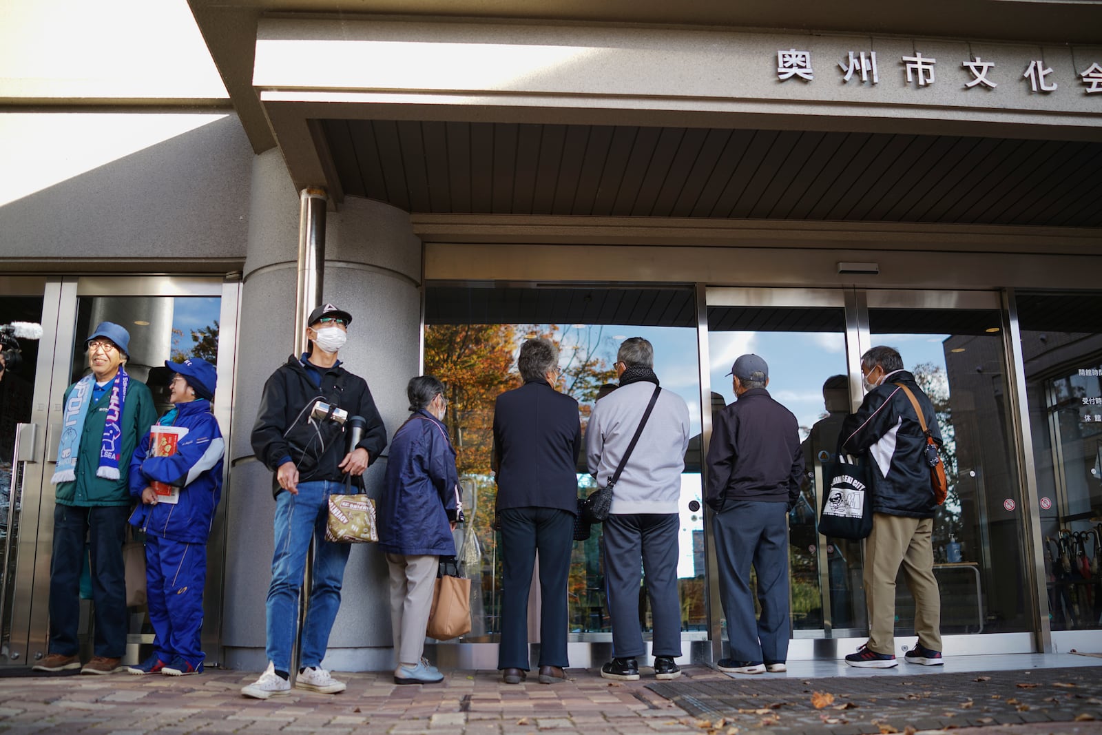 People wait in line to watch a live stream of Game 3 of the baseball World Series between the Los Angeles Dodgers and the New York Yankees, in a public viewing event in Oshu, northeastern Japan, the hometown of Shohei Ohtani of the Dodgers, Tuesday,Oct. 29, 2024. (AP Photo/Eugene Hoshiko)