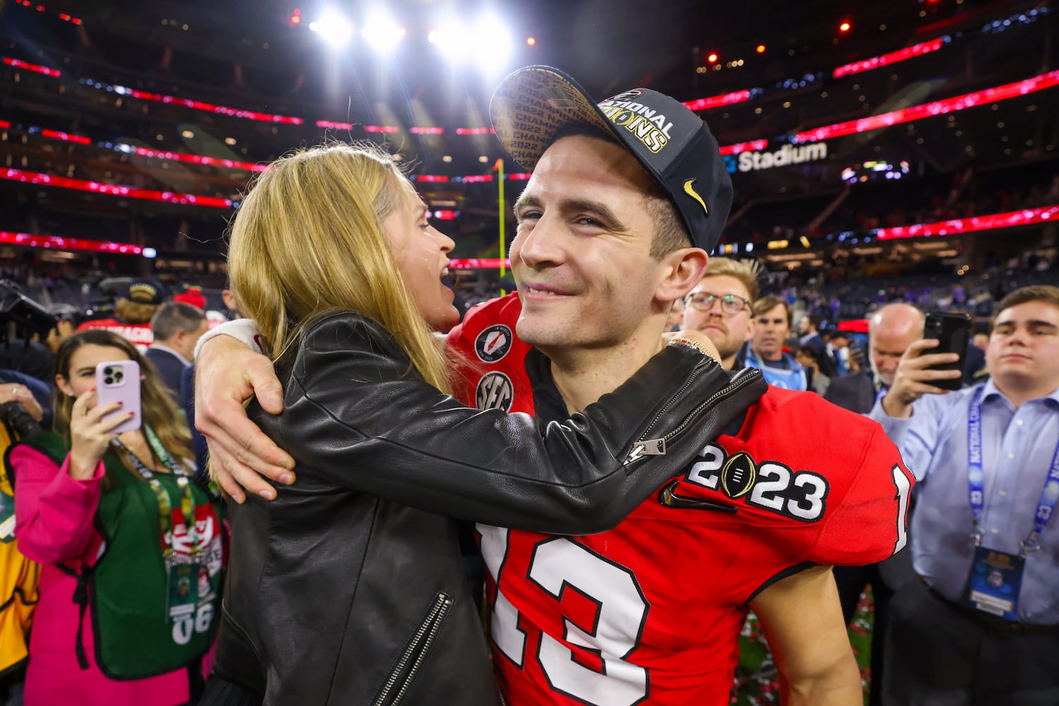 Georgia Bulldogs quarterback and offensive most valuable player Stetson Bennett (13) celebrates with  head coach Kirby Smart’s wife Mary Beth after defeating the TCU Horned Frogs 65-7 in the College Football Playoff National Championship at SoFi Stadium in Los Angeles on Monday, January 9, 2023 to secure a second consecutive national title. (Jason Getz / Jason.Getz@ajc.com)