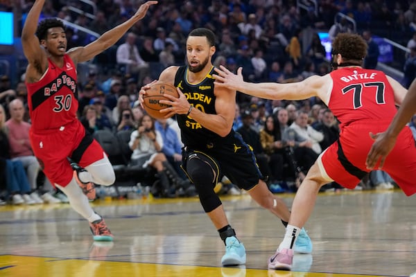 Golden State Warriors guard Stephen Curry, center, moves the ball between Toronto Raptors guard Ochai Agbaji (30) and forward Jamison Battle (77) during the first half of an NBA basketball game Thursday, March 20, 2025, in San Francisco. (AP Photo/Godofredo A. Vásquez)