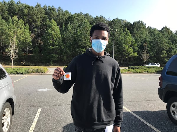 Anthony Sledge, 20, voted Tuesday in Gwinnett County and then flashed his voting sticker outside Anderson-Livsey Elementary School in Snellville. VANESSA McCRAY/AJC