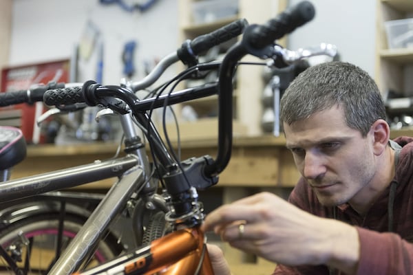 Andrej Ciho, 35, the manager of South Atlanta Bike Shop, repairs the handlebars on a customer’s bike. South Atlanta Bike Shop temporarily employs students from around the area. DAVID BARNES / SPECIAL