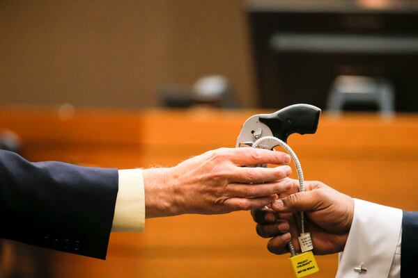 04/13/2018 -- Atlanta, GA - Criminal scene analyst Ross Martin Gardner, left, hands the gun used in the shooting of Diane McIver back to Fulton County Chief Assistant District Attorney Clint Rucker, right, during the nineteenth day of trial for Tex McIver before Fulton County Chief Judge Robert McBurney, Friday, April 13, 2018. ALYSSA POINTER/ALYSSA.POINTER@AJC.COM