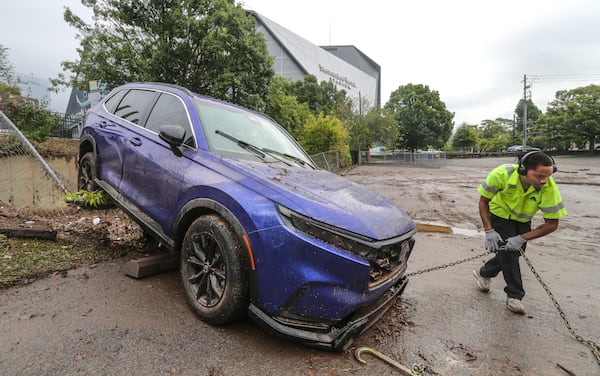 September 15, 2023 Atlanta: A-Tow driver Tobias Brown readies to pull away a lone Honda vehicle carried by flood waters into a church parking lot fence at Central United Methodist Church. (John Spink / John.Spink@ajc.com)
