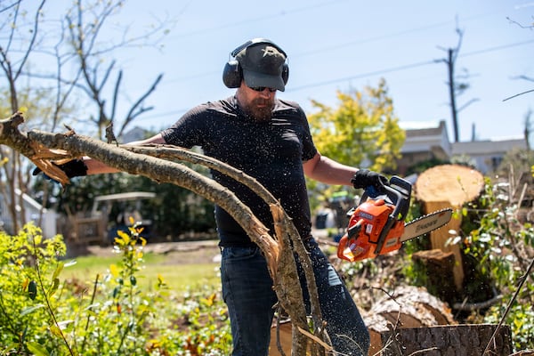 Jason Rose cleans up downed trees in the backyard of his mother’s property in Newnan. Volunteers have fanned out across Newnan to help, cleaning up debris and delivering meals. (Alyssa Pointer / Alyssa.Pointer@ajc.com)