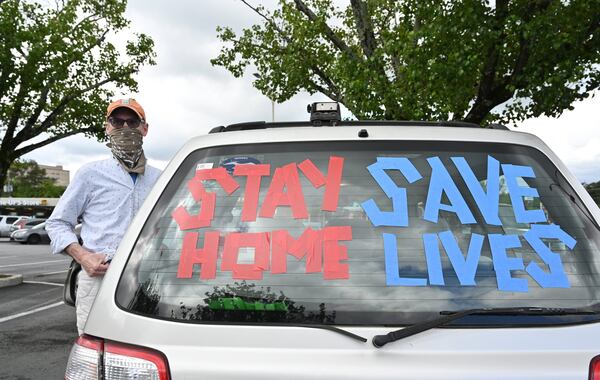 A protester decorates her car with signs as people gather for drive-by protest against Gov. Brian Kemp’ss decision to allow the reopening of some businesses.(Hyosub Shin/Hyosub.Shin@ajc.com)