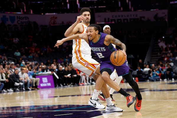 Charlotte Hornets guard Nick Smith Jr. (8) drives past Atlanta Hawks forward Georges Niang during the first half of an NBA basketball game in Charlotte, N.C., Tuesday, March 18, 2025. (AP Photo/Nell Redmond)