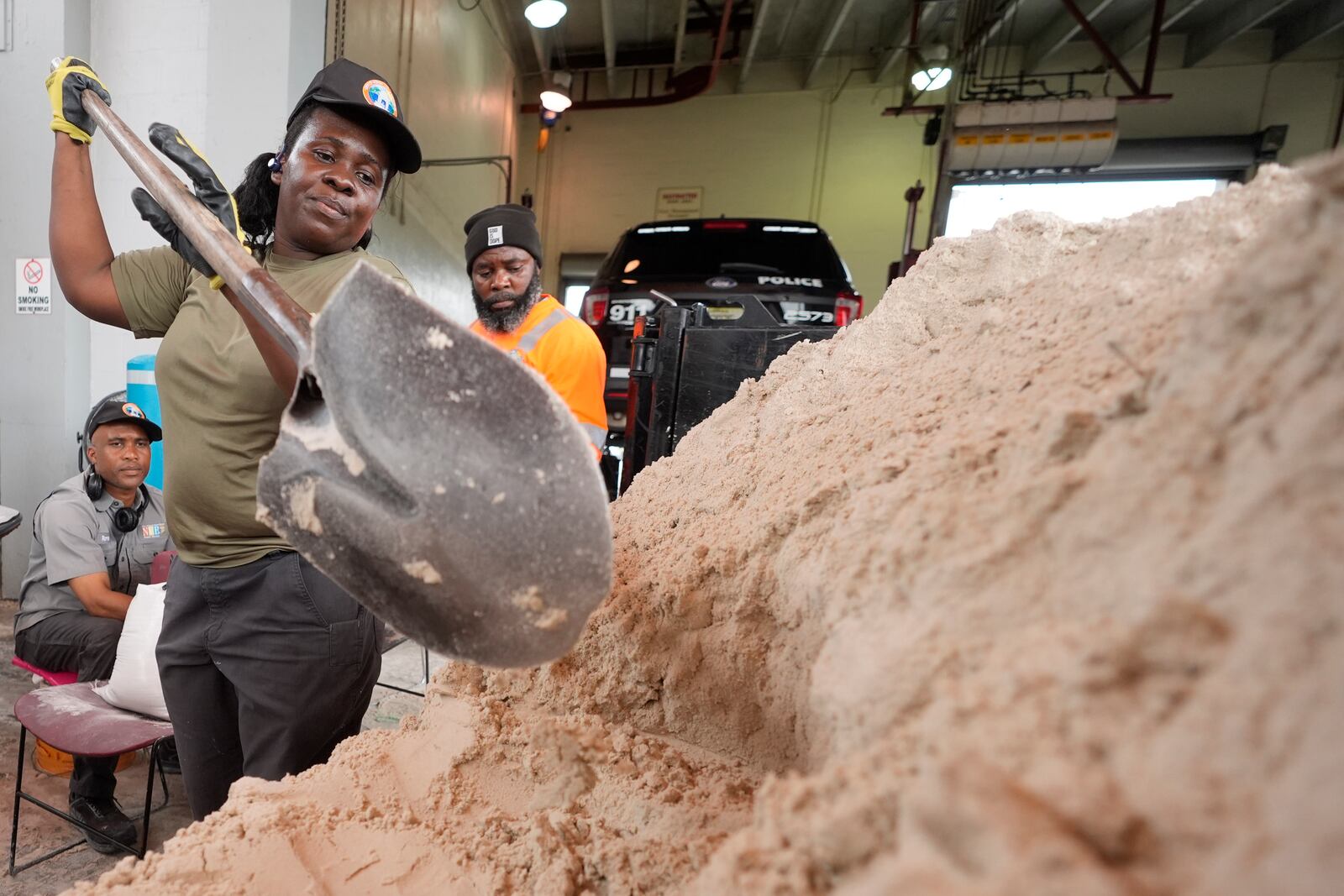 North Miami Beach, Fla., public service worker Annarose Bellefleur shovels sand as workers load sandbags, to distribute to residents to help prevent flooding, as Hurricane Milton prepares to strike Florida, Tuesday, Oct. 8, 2024, in North Miami Beach. (AP Photo/Wilfredo Lee)