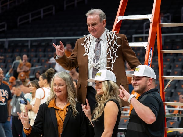 Texas Women's head basketball coach Vic Schaefer flashes the "Hook 'Em Horns" sign while wearing a net cut down after defeating Florida in an NCAA college basketball game, Sunday, March 2, 2025, in Austin, Texas. (AP Photo/Michael Thomas)