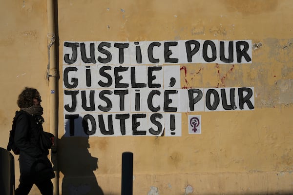 A woman walks past a poster "Justice for Gisele, Justice for all women", Saturday, Dec. 14, 2024 in Avignon, southern France, near the courthouse where the Mazan rape trial is taking place. (AP Photo/Aurelien Morissard)