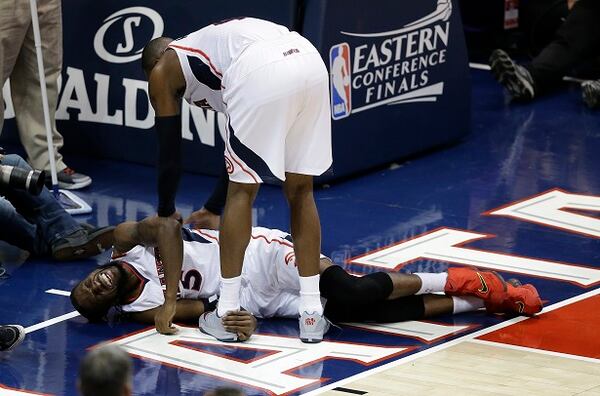 Atlanta Hawks forward DeMarre Carroll lies on the court as Atlanta Hawks forward Paul Millsap (4) speaks after Carroll was injured against the Cleveland Cavaliers during the second half in Game 1 of the Eastern Conference finals of the NBA basketball playoffs, Wednesday, May 20, 2015, in Atlanta. (AP Photo/David Goldman)