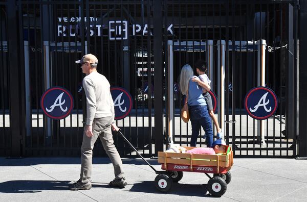 Baseball fans walk past a locked gate at Truist Park on Wednesday, March 2, 2022. (Hyosub Shin / Hyosub.Shin@ajc.com)