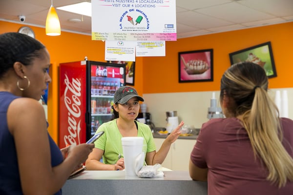 Manager Maritza Cantero (center) helps customers Shandale Brantley (left) and Erica Garcia (right) choose flavored popsicles at La Major de Michoacan, located at 403 Atlanta Highway, in Gainesville. (Alyssa Pointer/alyssa.pointer@ajc.com)