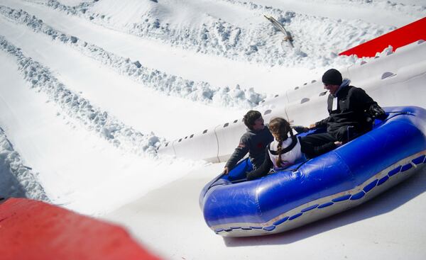 Darrel Corradino (right), his daughter Cali and son Coby ride a family sized tube down Snow Mountain inside Stone Mountain Park on Saturday, November 24, 2012. Snow Mountain has 20, 400 foot lanes for tubing, smaller tubing lanes for young children and a snow playground to build snowmen and forts.