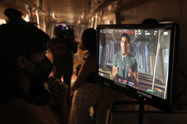 As shown on a monitor, Carlos Andres Gomez performs as the NEXT Movement films local artists and musicians on a MARTA train at MARTA’s Railyard, Tuesday, July 12, 2022, in Atlanta. In partnership with MARTA Artbound, the High Museum of Atlanta and others, the campaign will feature a photo exhibit/digital poster series and performances produced for the partners' digital media platforms in fall 2022. (Jason Getz / Jason.Getz@ajc.com) 