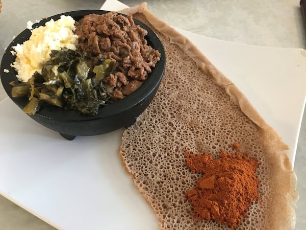 Bole Special Kitfo brings beef tartare seasoned with a chili spice blend called mitmita. The meat is served with house-made ayib (an Ethiopian cheese similar to cottage cheese) and collard greens. LIGAYA FIGUERAS / LFIGUERAS@AJC.COM