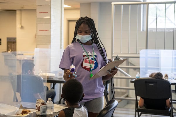 Camp counselor Jada Faulks takes a camper's temperature during lunch at the Hugh Grogan Community Center in Marietta, Thursday, June 10, 2021. The camp is sponsored by the Marietta Police Athletic League. (Alyssa Pointer / Alyssa.Pointer@ajc.com)