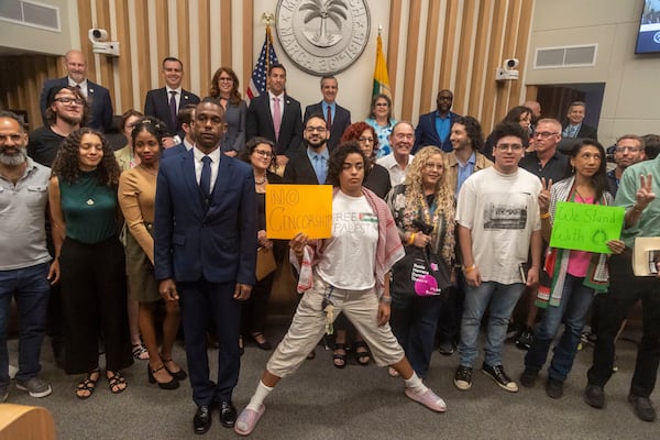 The Miami Beach City Commission poses along with people who attended the Commission Meeting after Miami Beach Mayor Steven Meiner withdrew resolution C7AA that would terminate O Cinema's lease and deferred resolution C7AB on Wednesday, March 19, 2025 in Miami Beach, Fla. (Jose Iglesias/Miami Herald via AP)