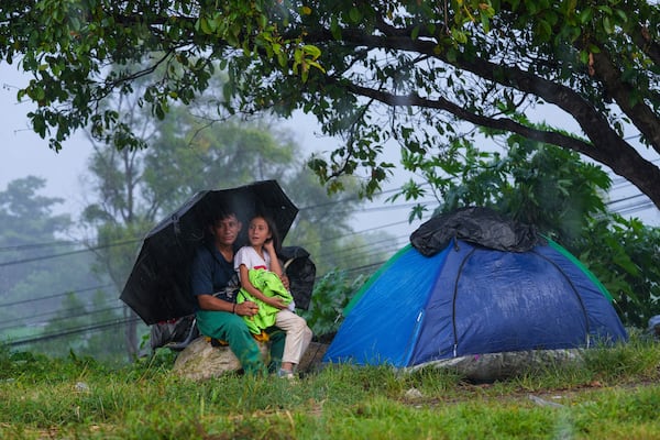 Migrants take cover from the rain after arriving at a makeshift shelter in Huixtla, Chiapas state, Mexico, Wednesday, Nov. 6, 2024, hoping to reach the country's northern border and ultimately the United States. (AP Photo/Moises Castillo)