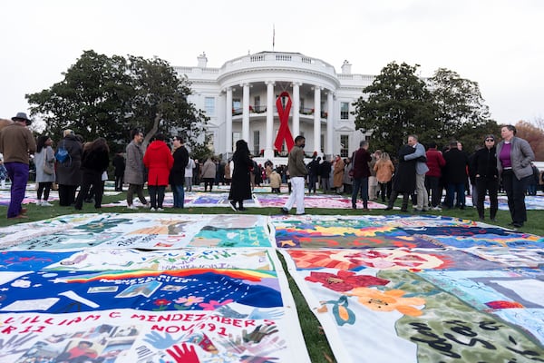 AIDS survivors, their families and advocates look at the display of AIDS Memorial quilts spread over the South Lawn of the White House during a ceremony to commemorate World AIDS Day, Sunday, Dec. 1, 2024, in Washington. (AP Photo/Manuel Balce Ceneta)