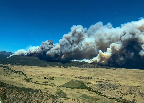 Plumes of smoke from a wildfire near Cimarron, N.M., rise in the background Friday, June 1, 2018. A wildfire raced across a swath of tinder-dry forest in northeastern New Mexico on Friday, sending up a thick plume of smoke that forced residents to flee their homes as heat and wind threatened to drive the flames.