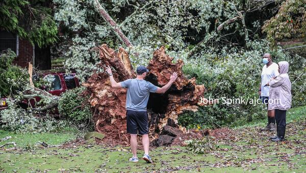 Homeowner Steven Schuerman (left) evaluates the damage after his tree fell on Jennifer and Darrell Winfrey’s truck (right) in the 2300 block of Beecher Road in southwest Atlanta.