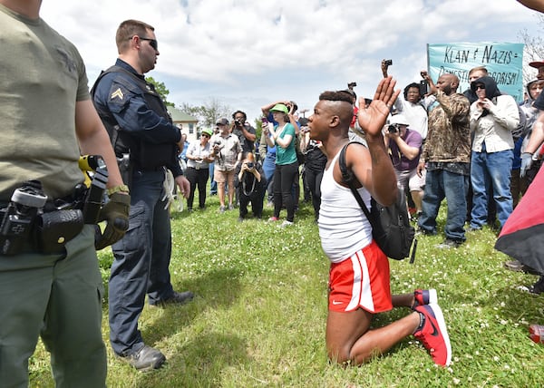 A counterprotester kneels with his hands up in front of law enforcement officers during a neo-Nazi rally at Greenville Street Park in downtown Newnan on Saturday, April 21, 2018.