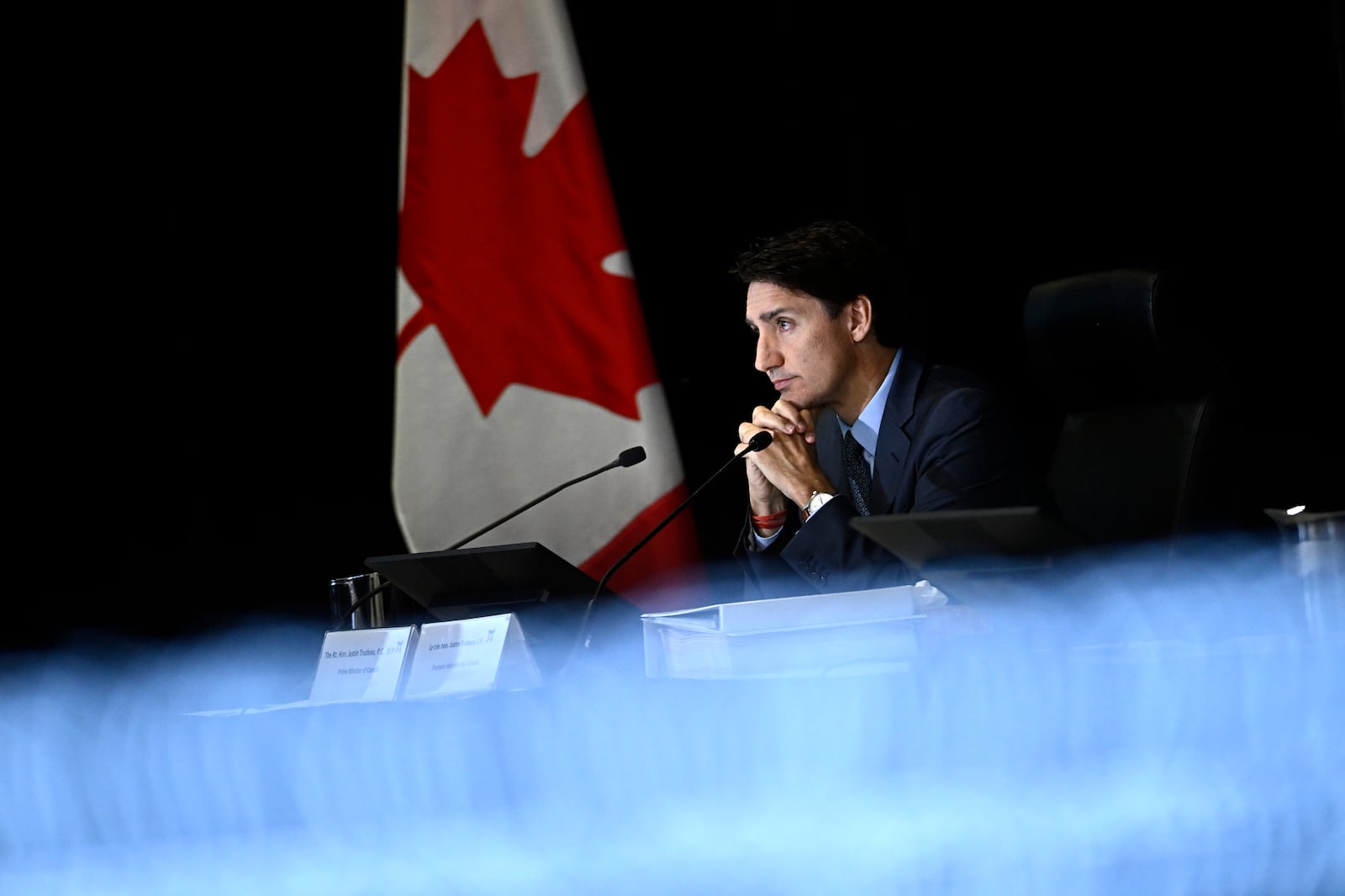 Prime Minister Justin Trudeau is seen past a TV screen showing a live transcription as he appears as a witness at the Foreign Interference Commission in Ottawa, Wednesday, Oct. 16, 2024. (Justin Tang/The Canadian Press via AP)