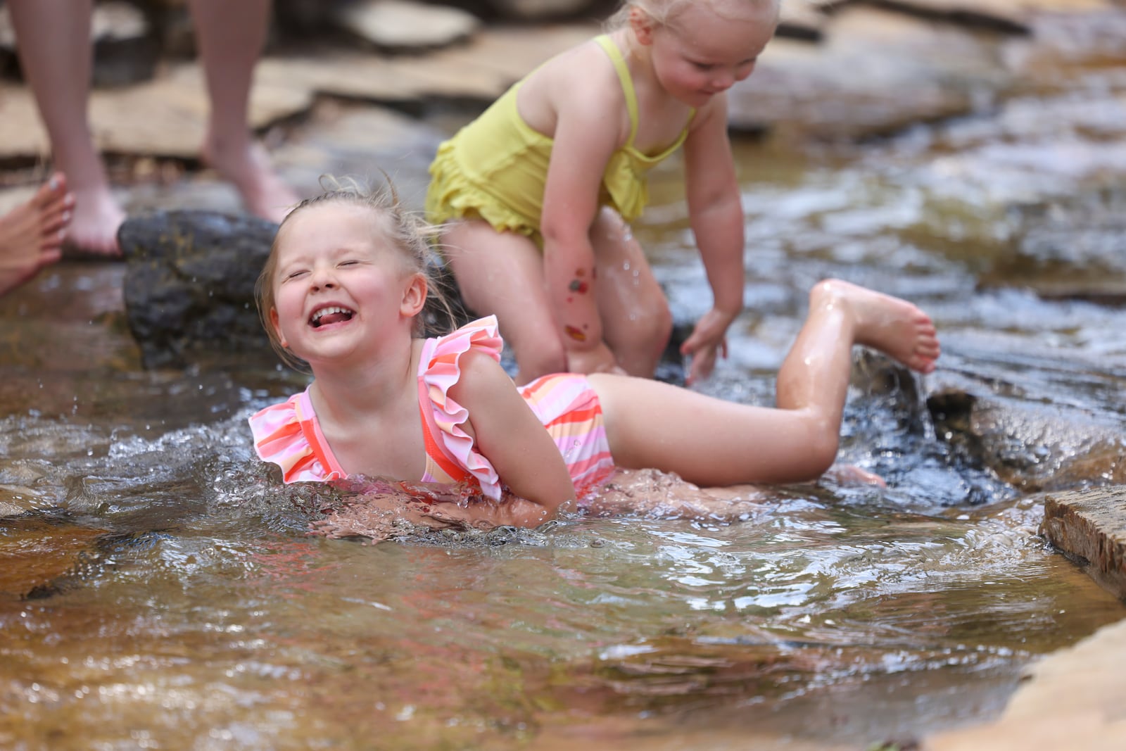 Four-year-old Nelle Boyd (center) and 2-year-old sister Scarlett play in the water at Dunwoody's Brook Run Park.