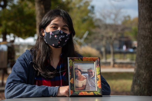 Mariana Palancares, 13, poses with a photo of her late father at Suwanee Town Center Park in Suwanee, Georgia, on Sunday, November 16, 2020. (Rebecca Wright for the Atlanta Journal-Constitution)