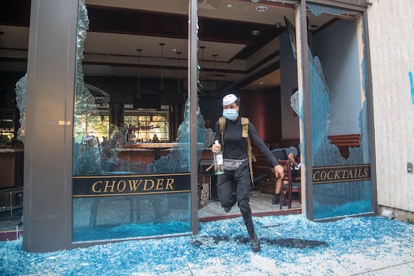 05/29/2020 - Atlanta, Georgia  - A protestor steals bottles of alcohol from McCormick & Schmick's Seafood Restaurant located in the CNN Center after a peaceful protest march turned into rioting and looting in Atlanta, Friday, May 29, 2020. (ALYSSA POINTER / ALYSSA.POINTER@AJC.COM)