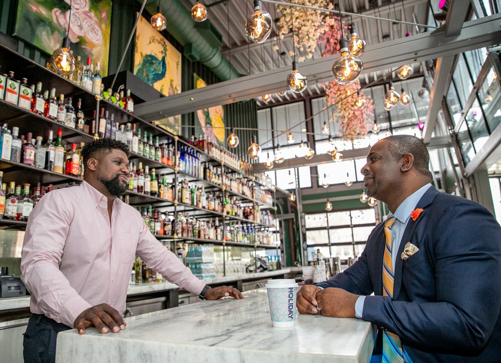 Investor Armond Davis, right, managing partner of The Paragon Group, and "A Seat at The Table Capital" owner Camaran Burke, left, catch up at Holiday Bar in West Midtown, one of Burke's four bars in Atlanta, on Wednesday, March 9, 2022.  Davis is an investor working with black-owned businesses to fill the gap many African Americans face when seeking financing.    Holiday Bar at Howell Mill and 14th offers coffee, cocktails and great patio space.  (Jenni Girtman for The Atlanta Journal-Constitution)