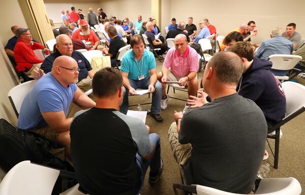 Men break into groups to discuss their Bible lesson during the Community Bible Church monthly study group at the American Heritage Gun Range in McDonough. CURTIS COMPTON / CCOMPTON@AJC.COM