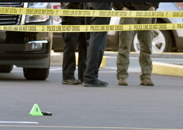 A gun lies on the ground inside a police barricade following a shooting at a Kroger grocery store that left two black customers dead Wednesday, Oct. 24, 2018, in Jeffersontown, Ky.  Gregory Alan Bush Sr., who is white, is charged with two counts of murder and 10 counts of wanton endangerment in the shooting, after which an armed bystander exchanged gunfire with Bush in the parking lot. No one was injured and Bush fled, but was taken into custody nearby a few minutes later.