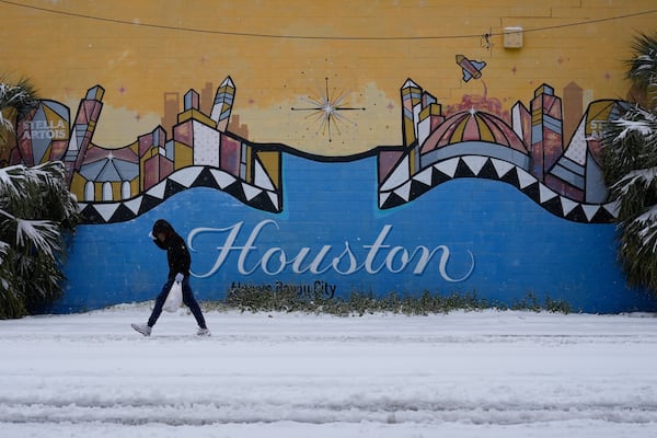 A person walks on a snow covered street Tuesday, Jan. 21, 2025, in Houston. (AP Photo/Ashley Landis)