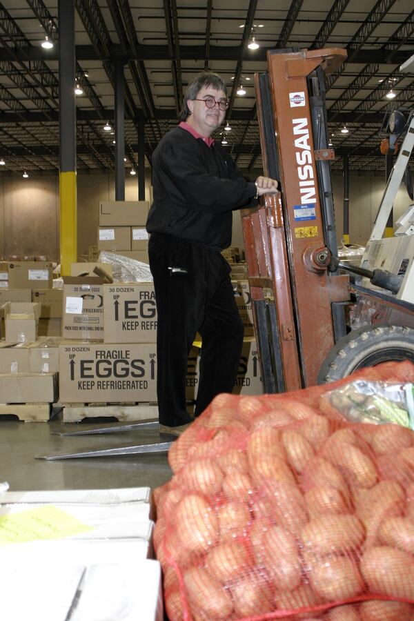 Pastor Joe Wingo among the canned, boxed and bagged foods that await shipment from the warehouse of Angel Food Ministries. SEAN DRAKES/Special