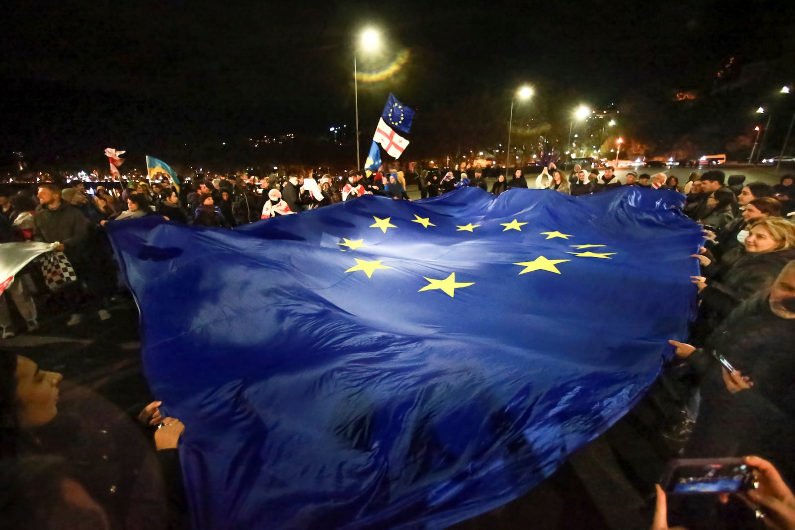 Protesters carry a huge EU flag during a rally against alleged violations in a recent parliamentary election in Tbilisi, Georgia, Monday, Nov. 4, 2024. (AP Photo/Zurab Tsertsvadze)