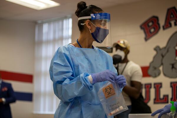 In this file photo, Clayton County Public Schools Nurse Supervisor Micah Sawyer packages a COVID-19 testing sample from an administrator during a Clayton County Public Schools COVID-19 vaccination and testing drive at G.P. Babb Middle School in Forest Park.  (Alyssa Pointer/Atlanta Journal-Constitution) 