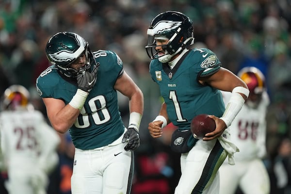 Philadelphia Eagles quarterback Jalen Hurts (1) is congratulated by teammate Dallas Goedert (88) after scoring during the second half of an NFL football game against the Washington Commanders Thursday, Nov. 14, 2024, in Philadelphia. (AP Photo/Matt Slocum)