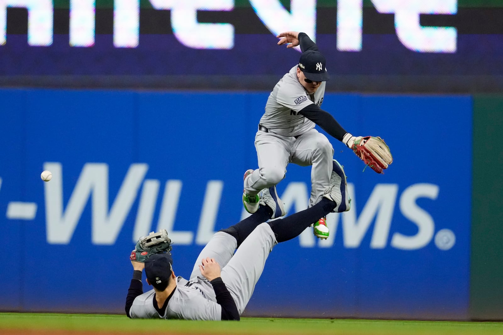 New York Yankees center fielder Aaron Judge, bottom, tries to catch a single by Cleveland Guardians' David Fry as left fielder Alex Verdugo leaps over him during the fifth inning in Game 5 of the baseball AL Championship Series Saturday, Oct. 19, 2024, in Cleveland. (AP Photo/Godofredo A. Vásquez)